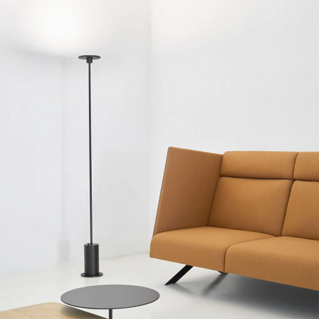 Black floor lamp Up by Arkoslight besides an armchair| Aiure