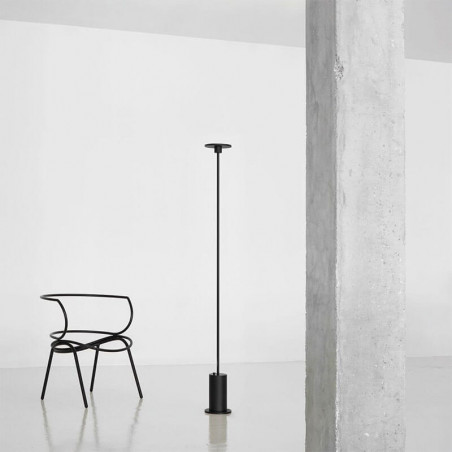 Black floor lamp Up by Arkoslight besides a chair| Aiure