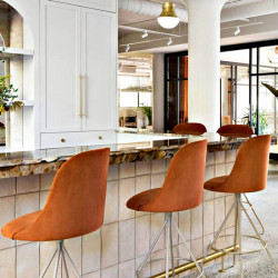 Aleta swivel bar stool high backrest by Viccarbe in an orange hue at a bar counter | Aiure