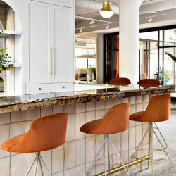 Tabouret de bar pivotant design Aleta de Viccarbe dans une teinte orange au comptoir d'un bar| Aiure